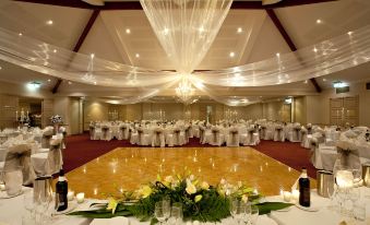 a large banquet hall with tables set for a formal event , white tablecloths , and gold decorations at Abbey Beach Resort