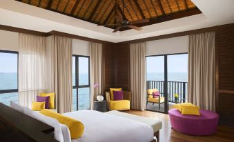 a luxurious hotel room with a large bed , yellow and purple seating , and an ocean view at Avani Sepang Goldcoast Resort