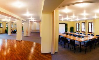 a large , empty conference room with wooden floors and yellow walls , containing multiple tables and chairs at Hotel Golfer