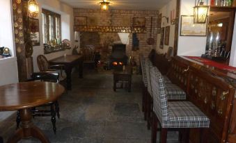 a dining room with wooden tables , chairs , and a brick wall , as well as a fireplace at Parrett Hotel