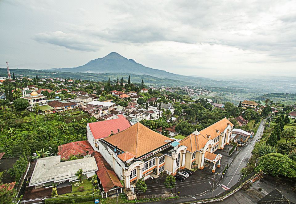 aerial view of a small town with a church and a mountain in the background at Royal Tretes View Hotel & Convention
