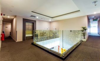 A spacious room features an indoor pool and a tiled floor, filled with natural light through glass windows at De Elements Business Hotel KL
