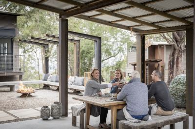 a group of people sitting at a dining table in a courtyard , enjoying a meal together at Spicers Sangoma Retreat