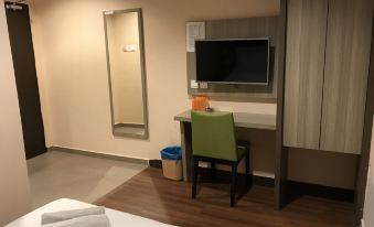 a hotel room with a bed , a desk , and a television mounted on the wall at Victory Hotel