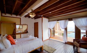 a spacious bedroom with a large bed and a view of the ocean through a window at The Sea Cliff Hotel Resort & Spa