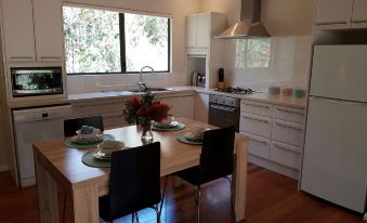 a modern kitchen with a dining table and chairs , as well as a sink and oven at Jarrah Grove Forest Retreat