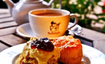 a cup of tea and a plate with scones and jam are on a table at The Snooty Fox