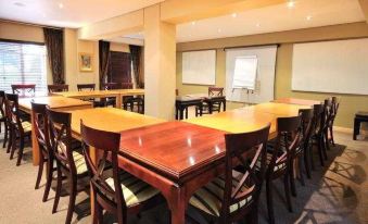 a conference room with wooden tables and chairs , a whiteboard , and two walls decorated with black decorations at Airport Inn and Suites