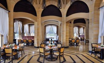 a large , well - lit room with multiple tables and chairs arranged for a group of people at Marriott Mena House, Cairo