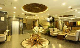a spacious , well - lit lobby with a staircase leading to the second floor and a large decorative ceiling at Prestige Hotel