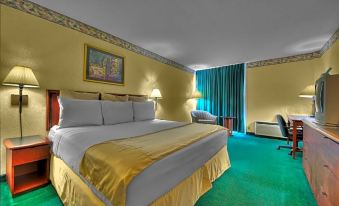 a large bed with a gold blanket and white pillows is in the middle of a room with green carpeting at Silver Beach Hotel