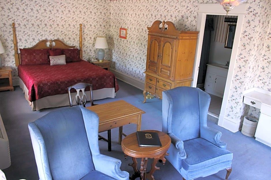 a cozy bedroom with a blue bed , red couches , and a wooden nightstand , surrounded by various furniture including chairs , a bed , at White Inn
