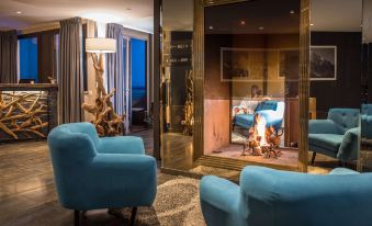 a cozy living room with two blue chairs , a fireplace , and a wooden floor , illuminated by warm lights at Everness Hotel & Resort