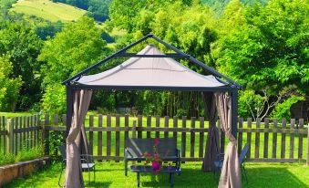 a backyard with a large gazebo surrounded by green grass and trees , providing a pleasant outdoor space at La Belle Verte