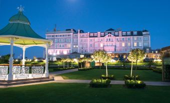 a large hotel surrounded by a lush green lawn , with a gazebo in the background at Cbh Hythe Imperial Hotel Golf and Spa