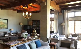 a spacious living room with wooden ceiling , large windows , and various furniture pieces including a couch , chairs , and a dining table at Parador de Verin
