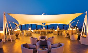 an outdoor dining area at a resort , with tables and chairs arranged for guests to enjoy their meals at Paloma Pasha