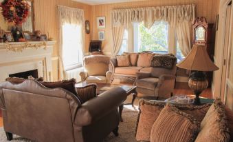 a cozy living room with brown leather couches , a fireplace , and multiple chairs arranged around it at Taylor Edes Inn