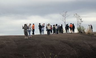 a group of people standing on a mountain top , taking pictures and enjoying the view at M Grand Hotel