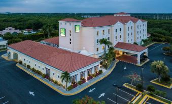 a large hotel with a red tile roof and multiple floors , surrounded by trees and parking lot at Quality Hotel Real Aeropuerto Santo Domingo