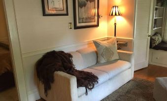 a white couch with a blanket on it is next to a lamp and a painting at PineCrest Inn