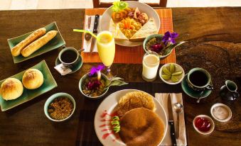 a dining table set with a variety of food items , including pancakes , fruit , and beverages at Tara Lodge Haven of Peace