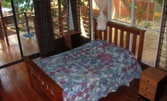 a wooden bed with a quilt on it , situated in a room with a view of the outdoors at Safari Lodge