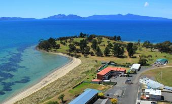 an aerial view of a beach with a house and trees near the water , surrounded by mountains at The Waterloo Hotel