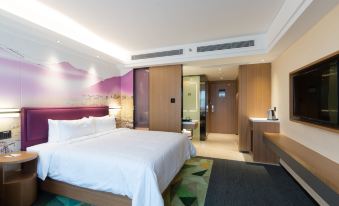The modern bedroom features a spacious bed and a sitting area in the center, elevated on a wooden platform at Hampton by Hilton Ji'an