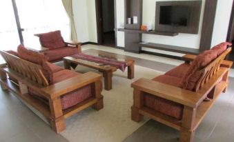 a living room with wooden furniture , including a couch and two chairs , and a television on a stand at Felda Residence Hot Springs