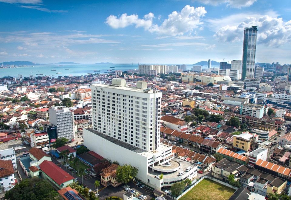 a large white building with a clock tower is situated in the center of a bustling city at Cititel Penang