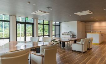 a large , open room with a wooden table and chairs , surrounded by windows and a bar at Okuhita Onsen Umehibiki