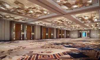 a large , empty conference room with high ceilings and gold ceiling lights , featuring geometric patterns on the floor at Omni Frisco-Dallas Hotel at the Star