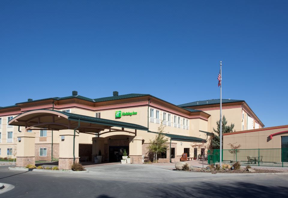 "a large building with a green sign that says "" holiday inn express "" and a flagpole in front of it" at Holiday Inn Rock Springs