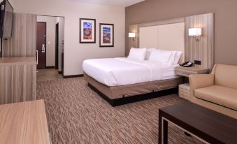 a large , neatly made bed is in a hotel room with a couch and telephone at Holiday Inn Express & Suites Williams