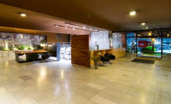 a modern , well - lit lobby with white - tiled floors and a wooden reception desk in the center at Hotel America Igualada