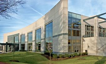 a large white building with a green lawn in front of it , surrounded by trees at Bethesda North Marriott Hotel & Conference Center