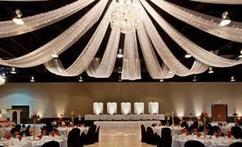 a large banquet hall with white drapes , chandeliers , and tables set for a formal event at Holiday Inn Wilmington