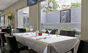 a dining room with a table set for two people , featuring white tablecloth and wine glasses at Argus Hotel Darwin