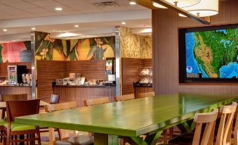 a dining area with a long green table and chairs , as well as a television mounted on the wall at Comfort Suites