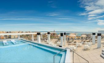 a rooftop pool with a view of the ocean and sky , surrounded by lounge chairs and umbrellas at Estudios RH Vinaros