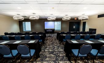 a large conference room with multiple rows of chairs arranged in a semicircle , and a projector screen mounted on the wall at Holiday Inn Grand Haven-Spring Lake