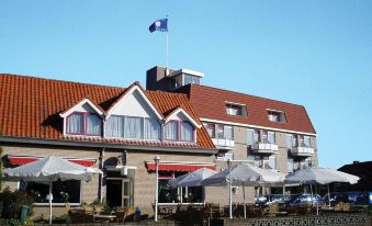 a large hotel building with a red tile roof and a french flag flying atop it at Fletcher Hotel Restaurant de Gelderse Poort