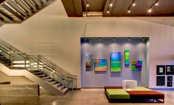 an art gallery with multiple paintings on display , including one of a blue background and several large pieces of art on the walls at Aloft Leawood-Overland Park
