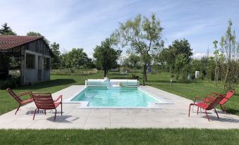 a small , rectangular pool surrounded by a grassy area with two red lounge chairs and a white water fountain at La Parenthèse