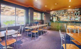 a restaurant with a purple and blue checkered floor , wooden tables and chairs , and a bar counter at Archibald Hotel