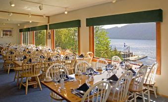 a large dining room with wooden tables and chairs , a view of a lake outside the window at Waterfall Resort