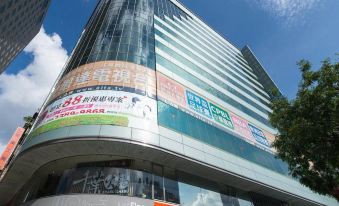 a large glass building with a green sign on the side , located in a city at Just Sleep Ximending