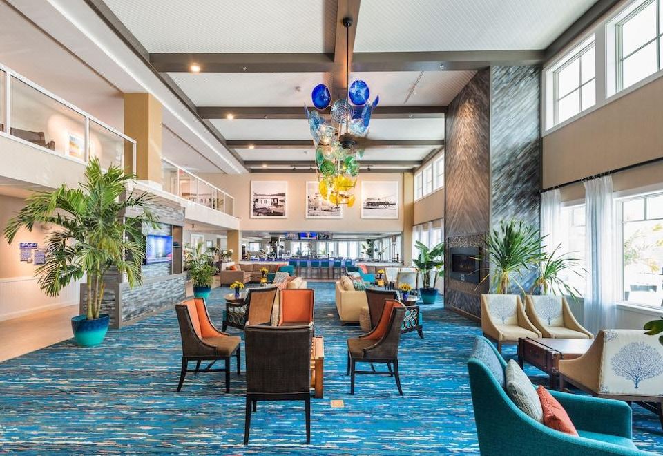 a large , brightly lit hotel lobby with various seating options , including couches , chairs , and a dining table at Bethany Beach Ocean Suites Residence Inn