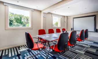a conference room with a table surrounded by chairs and a large window allowing natural light to enter at Holiday Inn Sittingbourne